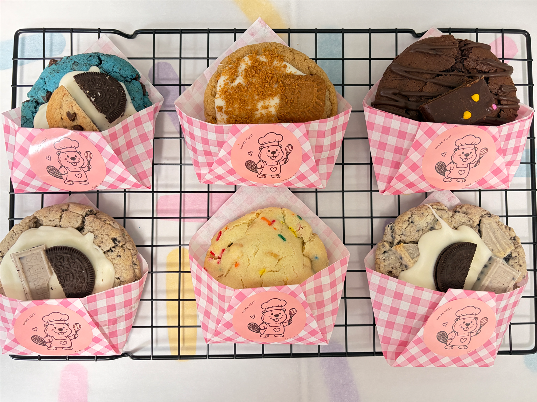 Sweet Beaver cookies individually packaged in pink wrappers on a cooling rack